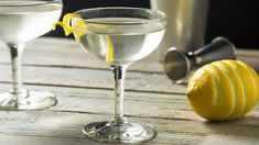 two martini glasses with lemon wedges next to each other