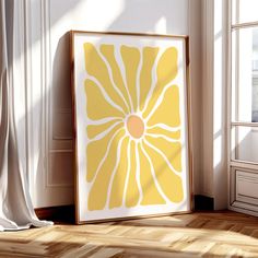 a yellow and white art print sitting on top of a wooden floor next to a window