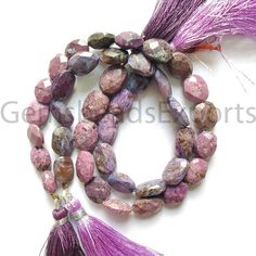 purple beads with tassels are displayed on a white surface