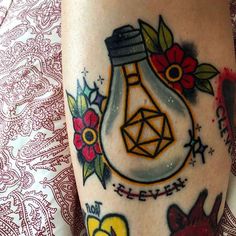 a tattoo on someone's leg with an image of a light bulb and flowers