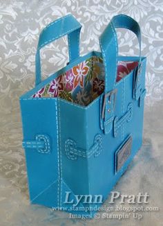 a small blue bag is sitting on a white tablecloth and it has two handles