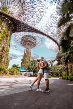 two people are kissing in front of the trees at gardens by the bay, singapore