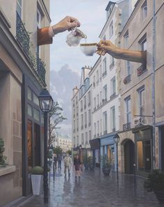 two hands reaching for something in the air above a city street with buildings and people