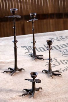 four metal candlesticks sitting on top of a table