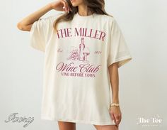 a woman wearing a t - shirt that says the miller wine club and has a glass in her hand