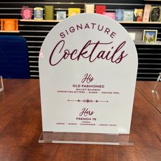 a sign that says signature cocktails is on a table in front of some shelves