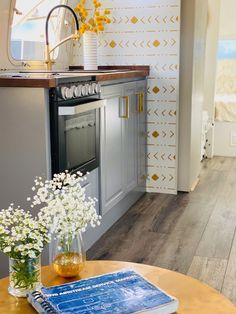 a kitchen with an oven, table and flowers in vases on the counter top