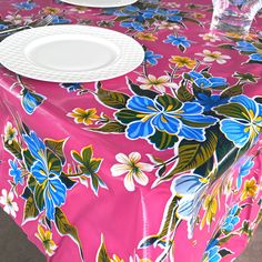 a pink table cloth with blue and yellow flowers on it, along with white plates