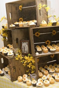 a table topped with lots of cupcakes covered in frosting and sunflowers