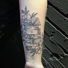 a tattoo on the arm of a woman with books and flowers