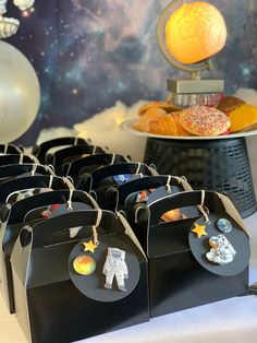 there is a space themed party on the table with donuts and other items in black bags