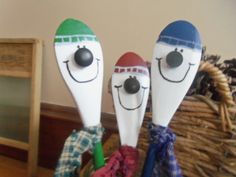 three wooden spoons with faces on them sitting in a basket next to a mirror