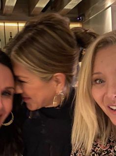 two women smile as they pose for a photo with another woman in front of them