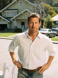 a man standing in front of a house with his hands on his hips and looking at the camera