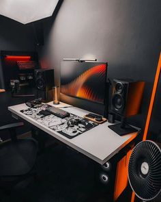 there is a desk with speakers on it and a fan in front of the monitor