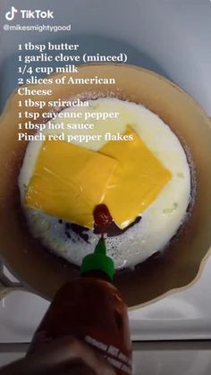 an egg is being cooked in a frying pan with cheese on top and other ingredients to make it