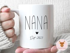 a person holding a white coffee mug with the name nanna on it in black ink