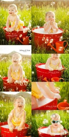 a baby sitting in a red tub filled with water and bubbles, surrounded by green grass