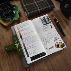 an open book sitting on top of a wooden table next to headphones and other items