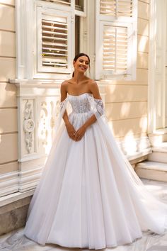 a woman in a white wedding dress posing for the camera with her hands on her hips