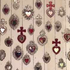 many heart shaped brooches are hanging on the wall with crosses and hearts attached to them