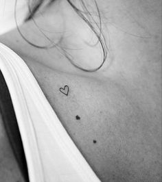 a black and white photo of a woman's chest with a heart tattoo on it