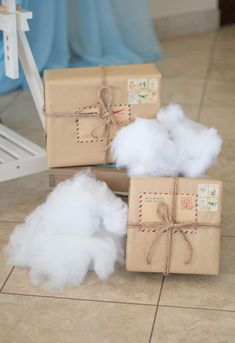 three wrapped presents sitting on top of a pile of cotton floss and tied with twine