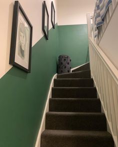 the stairs are painted green and white with black frames on each side, along with pictures hanging on the wall