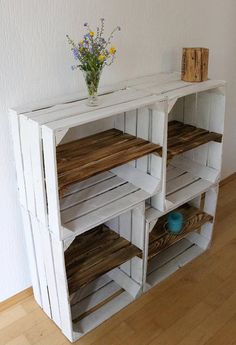 a white shelf with wooden shelves and flowers on top