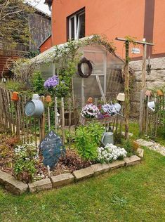 an outdoor garden area with various plants and flowers in the center, along with a house behind it