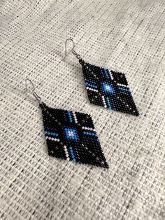 black and blue beaded earrings sitting on top of a white cloth