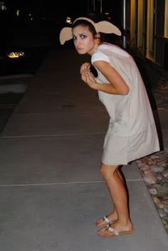 a woman standing on the sidewalk wearing sandals and a bunny ears headband at night