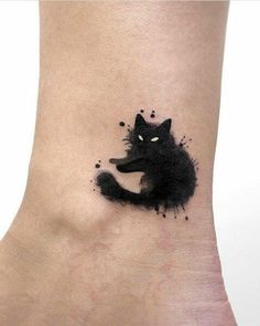 a black cat tattoo on the ankle with watercolor paint splatters all over it