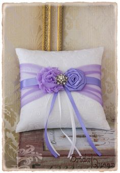 a white pillow with purple flowers on it and a ribbon tied around the front of it