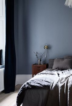 a bed sitting in a bedroom next to a window with curtains on the windowsill