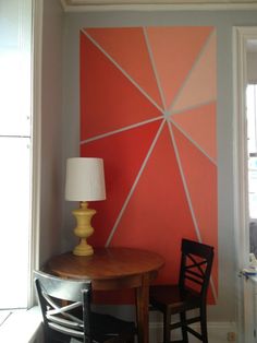 an orange and white wall in a dining room with two chairs next to a table