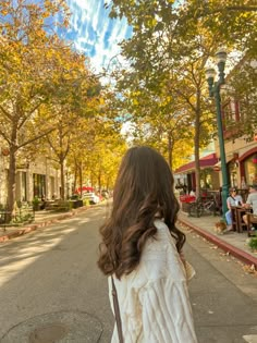 a woman is walking down the street with her back to the camera and looking up