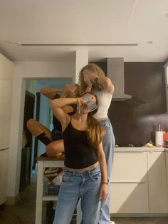 three women standing in a kitchen with one holding a can and the other sitting down