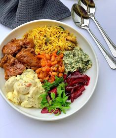 a white plate topped with different types of food next to silverware and utensils