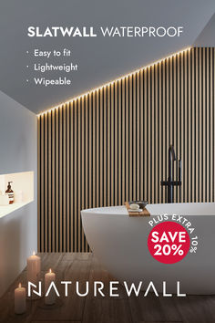 a bathroom with a tub and candles on the floor, next to a wall that has vertical wood slats