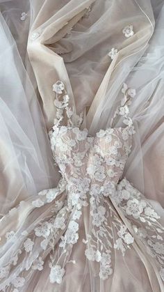 the back of a wedding dress with white flowers and sheer organe fabric on it