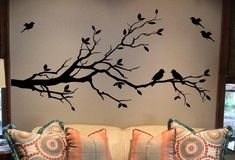 a living room with a couch and tree branch decal on the wall