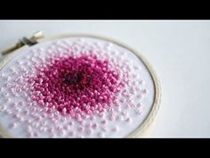 a close up of a pink and white object in a embroidery hoop on a table