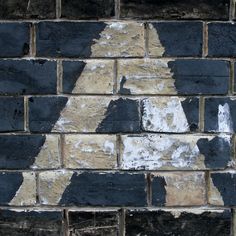 a black and white brick wall with peeling paint on it's edges, showing the shape of an arrow