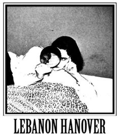 a woman laying on top of a bed next to a black and white poster with the words lebanon hangover