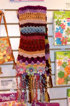 there are many crocheted bags hanging on the wall together, including one with flowers