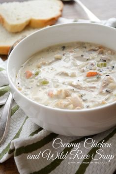 a bowl of chicken and wild rice soup on a table next to some slices of bread