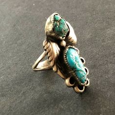 "VINTAGE NAVAJO RING DESCRIPTION: This gorgeous ring is by legendary Navajo artisan David K Lister. Two breathtaking specimens of natural turquoise are secure in micro serrated bezel, flanked by applied leaves, on a foundation oh heavy gauge vintage sterling silver. PLEASE NOTE that the larger of the two cabs has a hairline fissure. The turquoise is secure in its setting. This ring will be a treasured addition to your collection of fine vintage Native American jewelry. MEASUREMENTS: Ring face me Antique Turquoise Anniversary Ring, Artisan Rings With Patina For Collectors, Turquoise Ring With Patina For Anniversary, Anniversary Turquoise Ring With Patina, Antique Turquoise Adjustable Rings, Vintage Oval Turquoise Ring, Vintage Untreated Oval Emerald Ring, Vintage Oval Untreated Emerald Ring, Vintage Oval Natural Emerald Ring