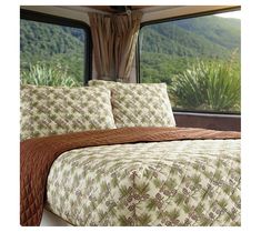 a bed in a room with a window overlooking the mountains and trees on both sides