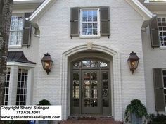 a large white brick house with shutters on the front door and windows above it